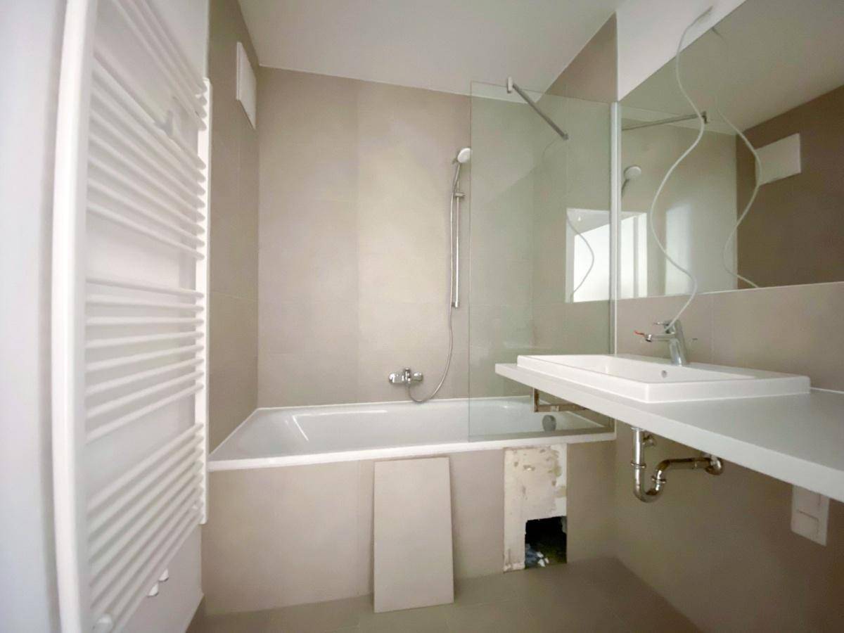 Modernes Badezimmer mit Badewanne, Duschbereich, Einzelwaschbecken und Handtuchheizkörper.
