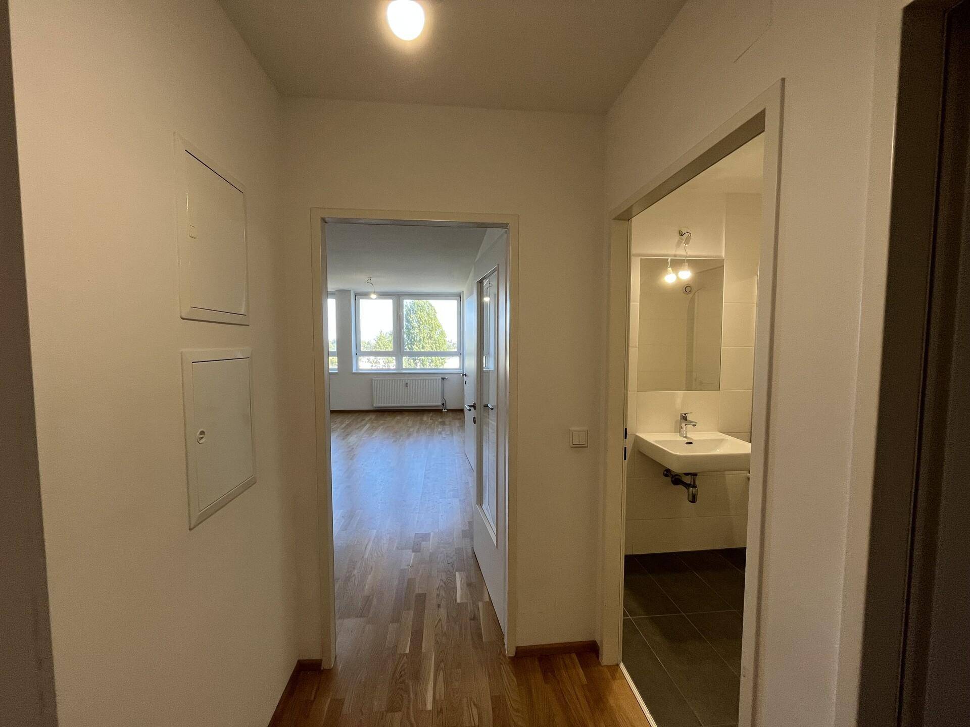 Heller Flur mit Holzboden, der zu den verschiedenen Räumen der Wohnung führt.