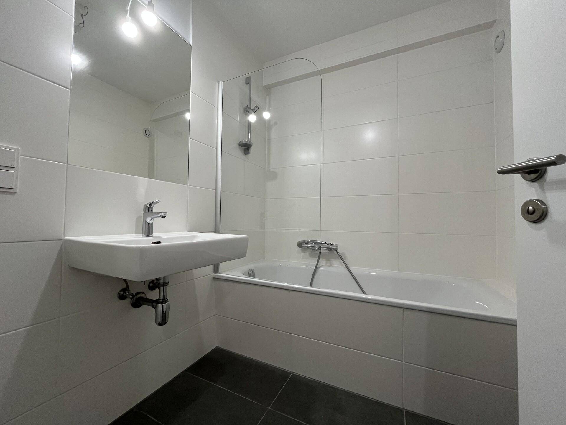 Modernes Badezimmer mit Badewanne, Waschbecken und weißen Fliesen.