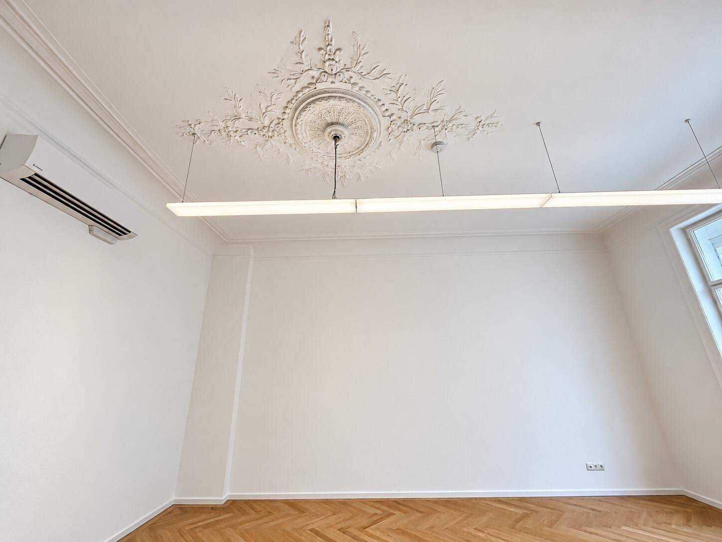 Detailansicht der hohen Decke mit Stuckverzierung und einer modernen Klimaanlage.