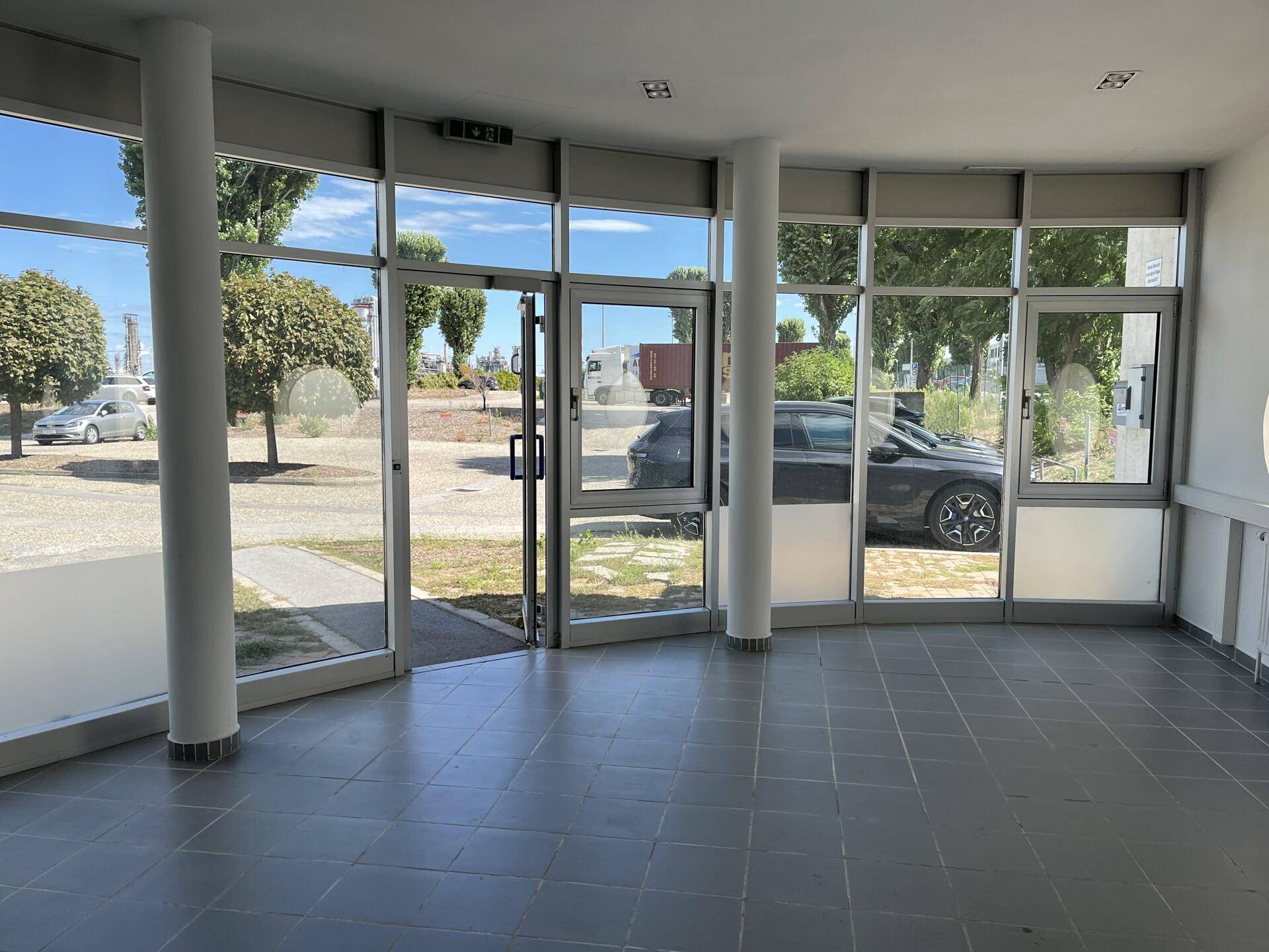 Eingangsbereich mit großer Glasfassade, die viel Tageslicht hereinlässt und einen grünen Ausblick bietet.