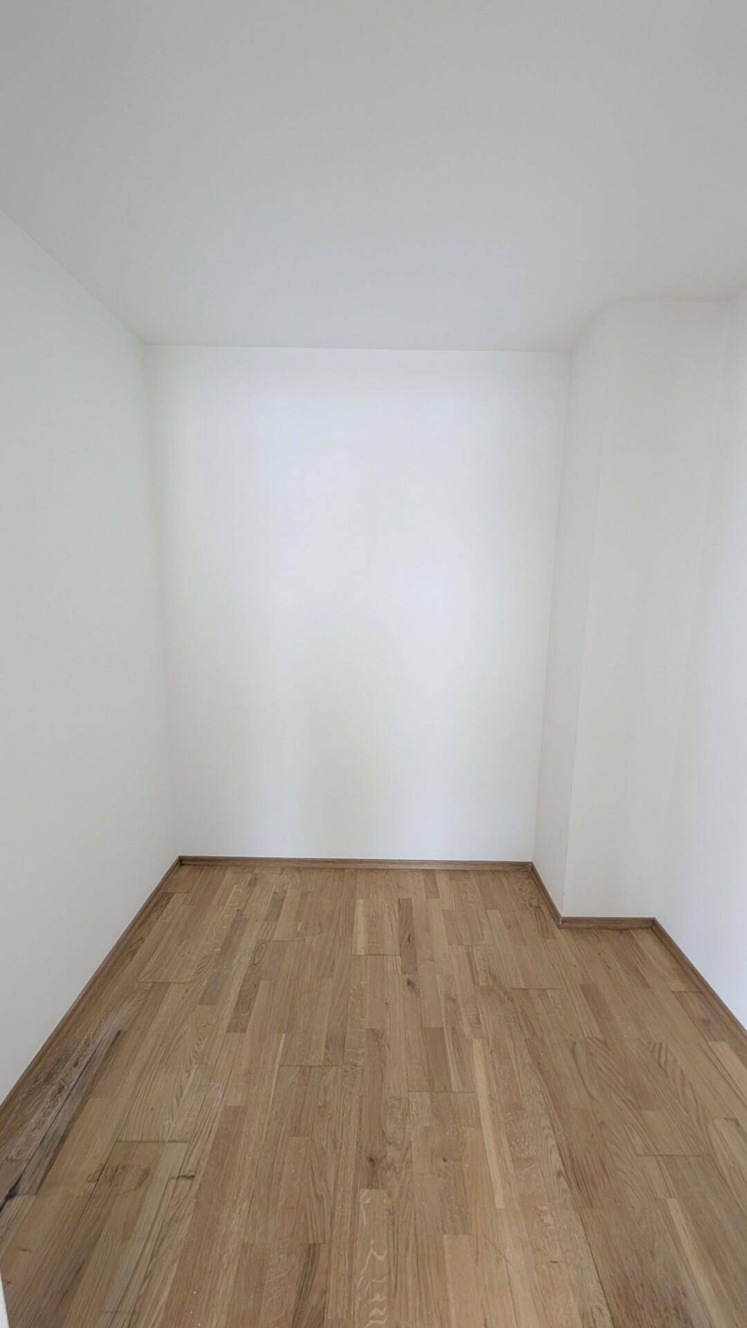 Kleiner Raum mit hellem Parkettboden und weißen Wänden, vielseitig nutzbar.