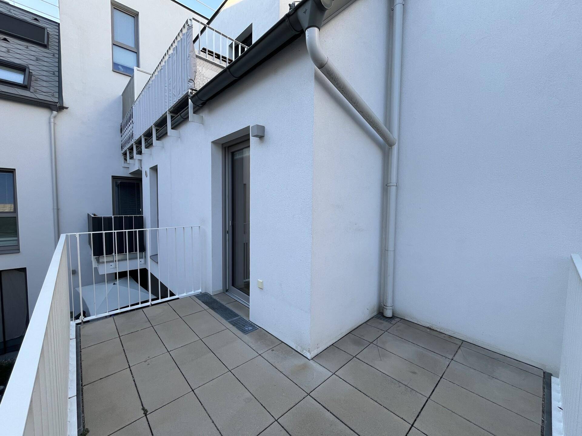 Kleiner Balkon mit Fliesenboden und Blick auf die Gebäudefassade.