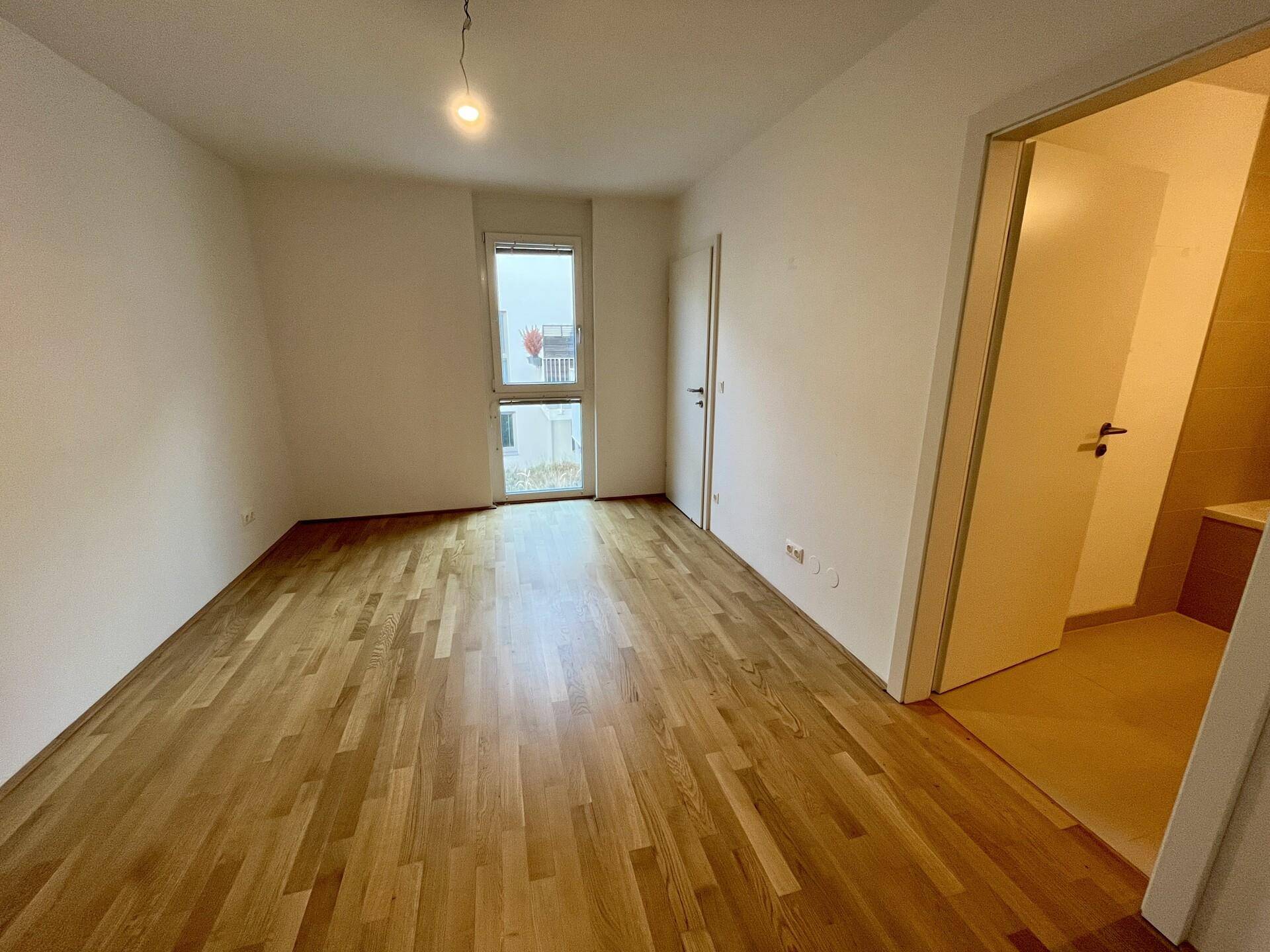 Helles Schlafzimmer mit Holzparkettboden und direktem Zugang zu einem Badezimmer.