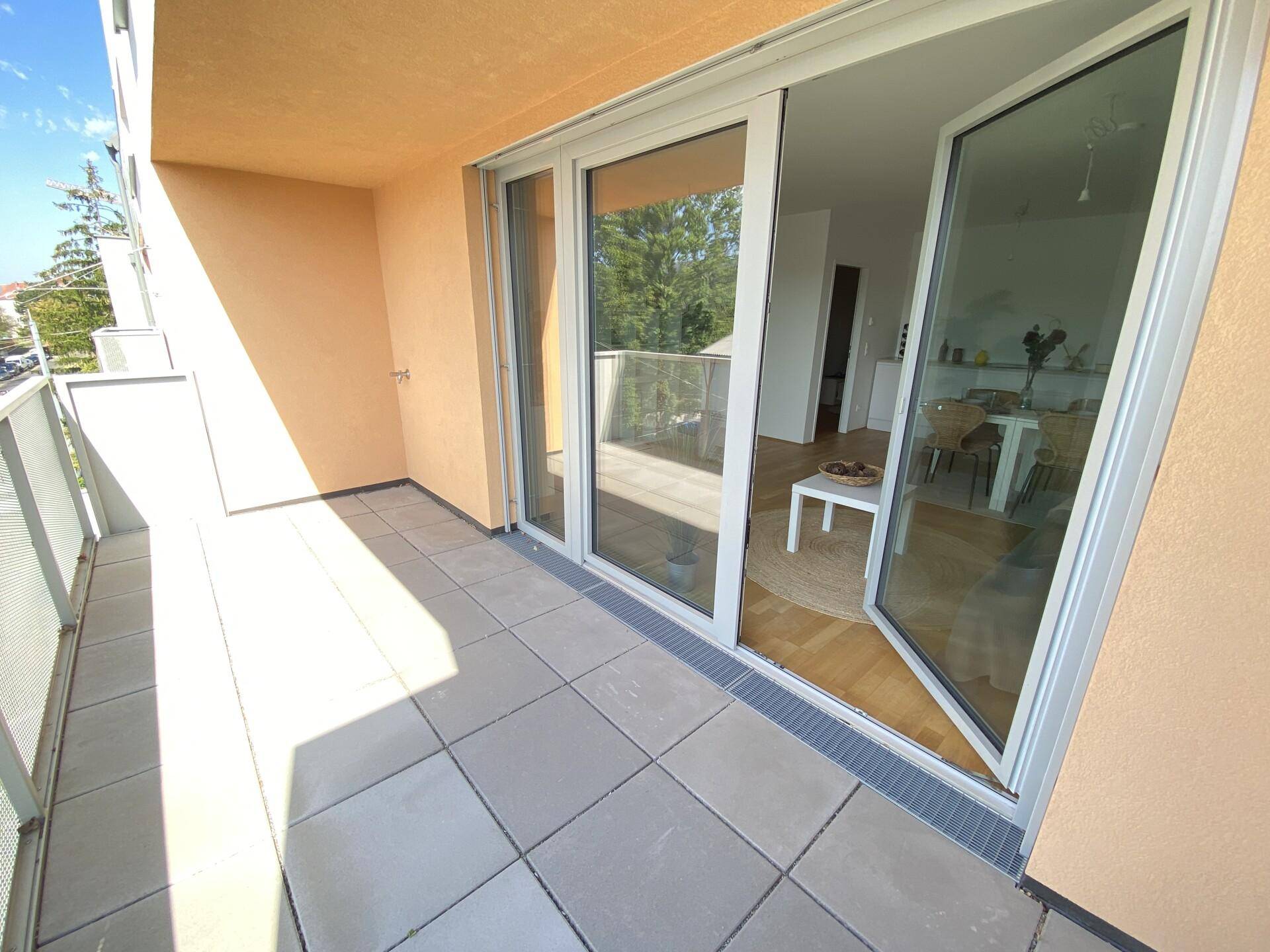 Geräumiger Balkon mit Fliesenboden und Blick auf die Umgebung, zugänglich vom Wohnbereich.