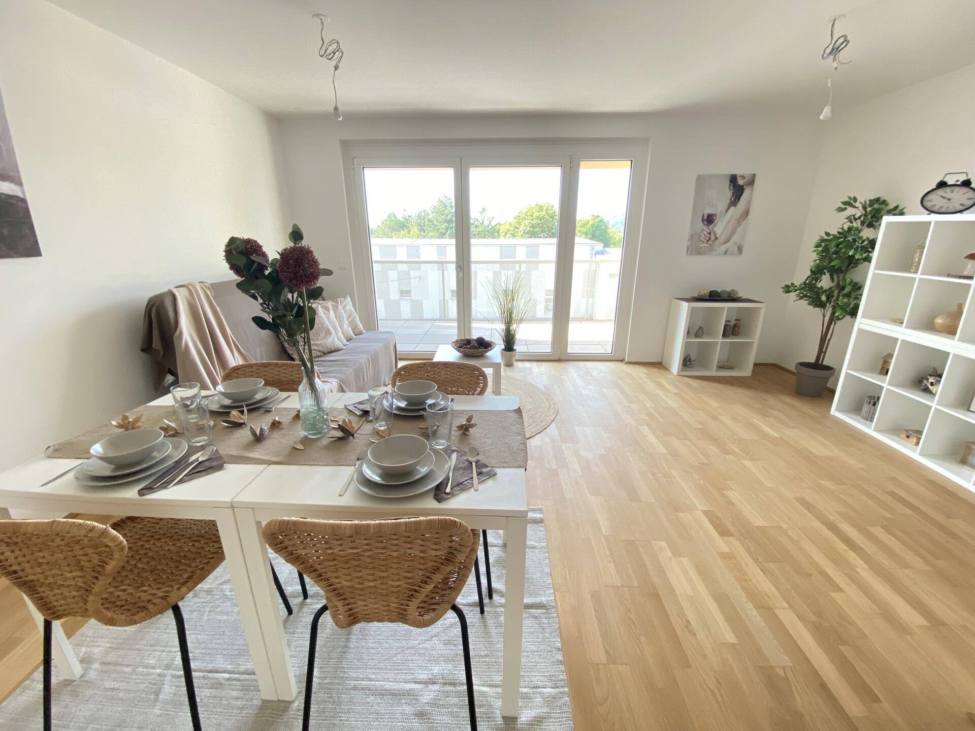 Heller Wohn- und Essbereich mit Holzboden, modernem Regal und Zugang zum sonnigen Balkon.