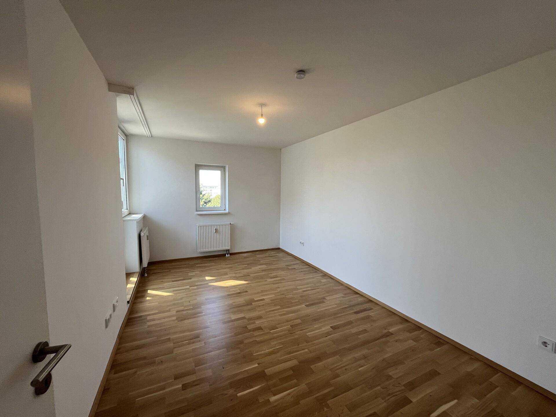 Geräumiges Zimmer mit Parkettboden und einem Fenster für natürliches Licht.