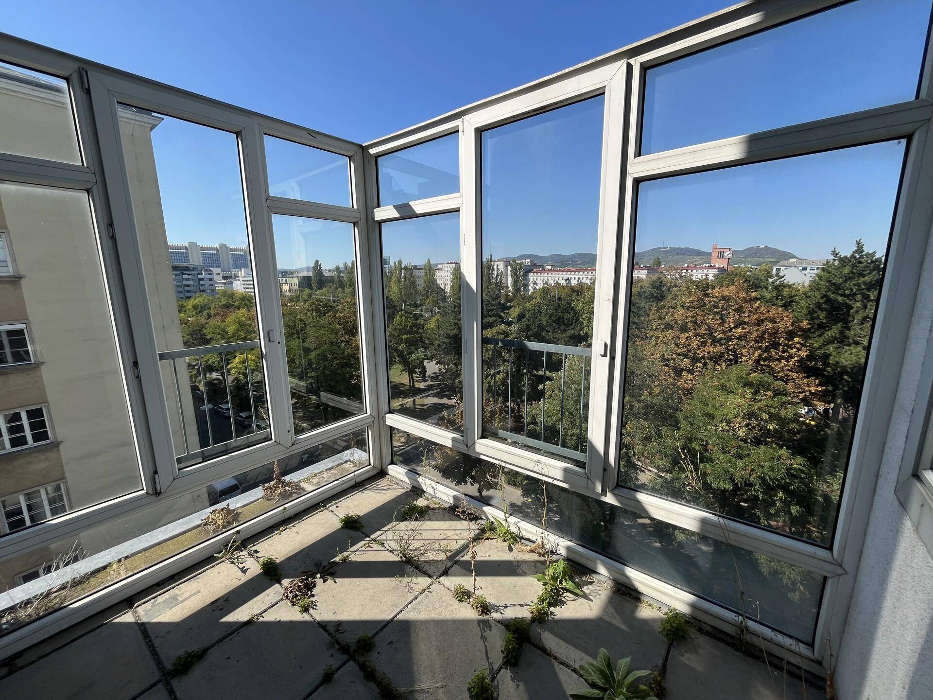 Verglaste Loggia mit Blick auf die Stadt und die umliegenden Bäume.