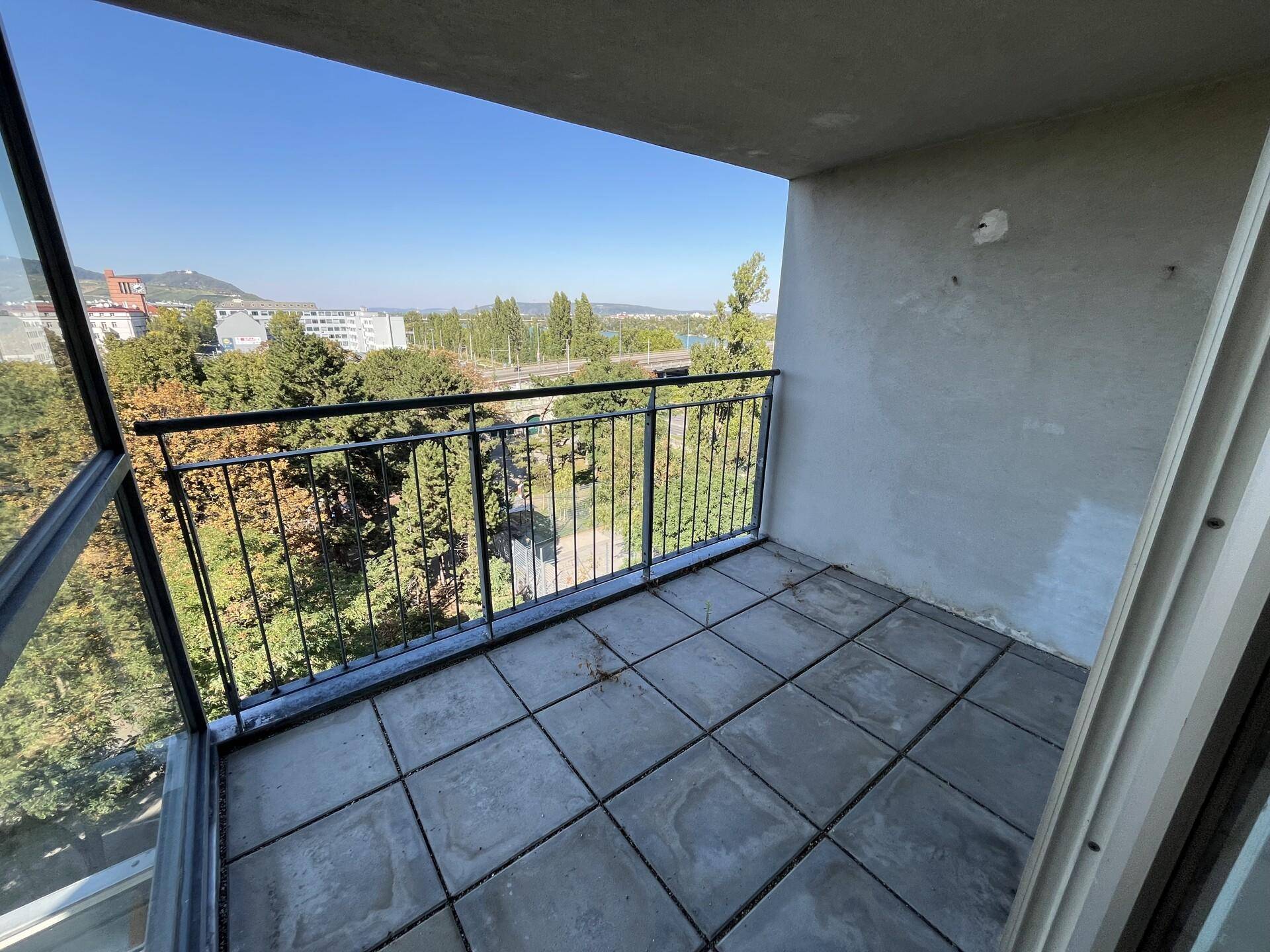 Kleiner Balkon mit Fliesenboden und Blick auf die grüne Umgebung.