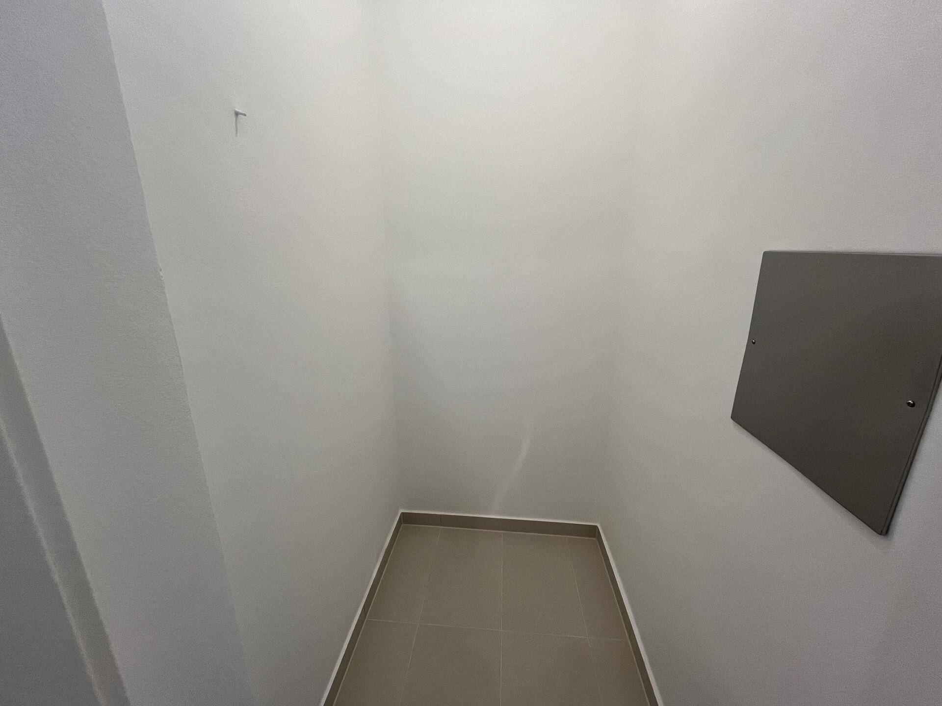 Praktischer Abstellraum mit Fliesenboden und weißen Wänden für diverse Gegenstände.