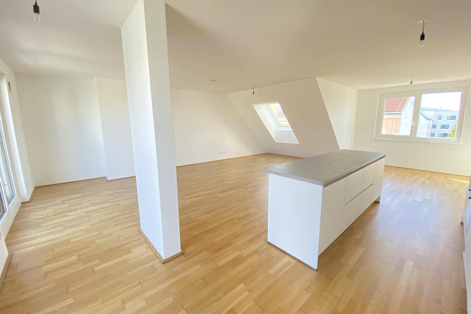 Geräumiger offener Wohnbereich mit Parkettboden, Dachschrägen und viel natürlichem Licht.