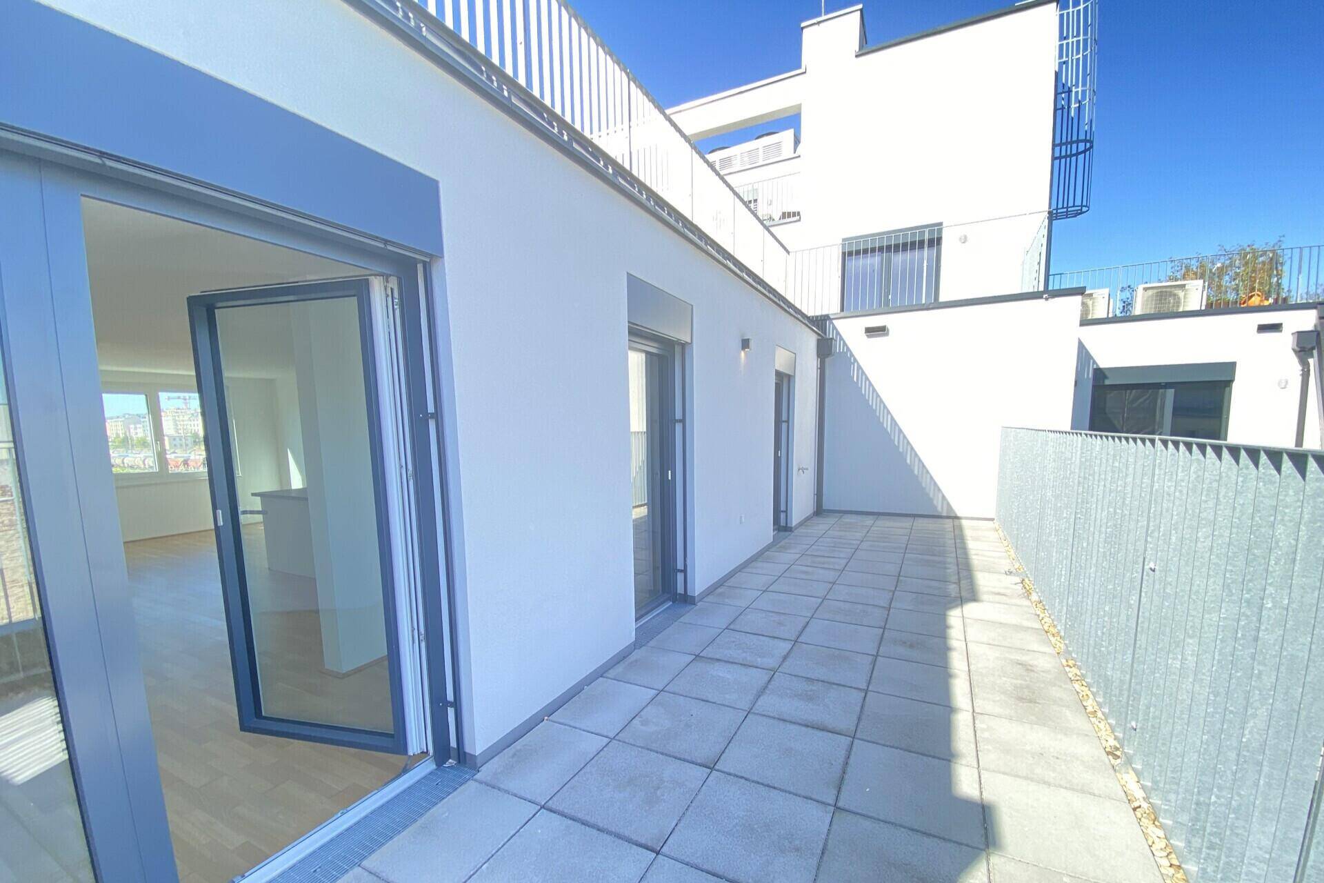 Sonniger Terrassenbereich mit Fliesenboden und direktem Zugang zum hellen Innenraum der Wohnung.