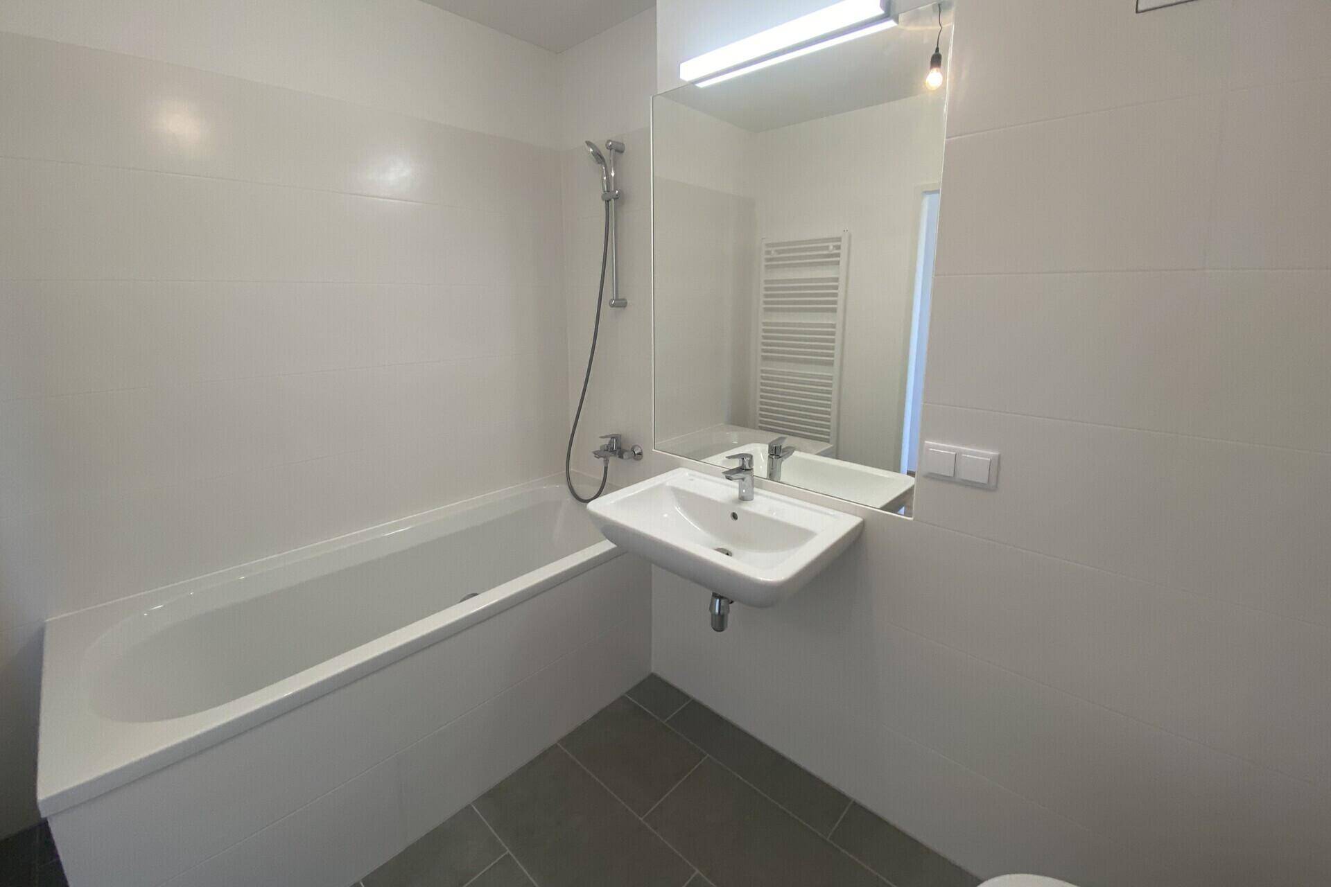 Zeitgemäßes Badezimmer mit Badewanne, Duscharmatur und einem praktischen Einzelwaschbecken.