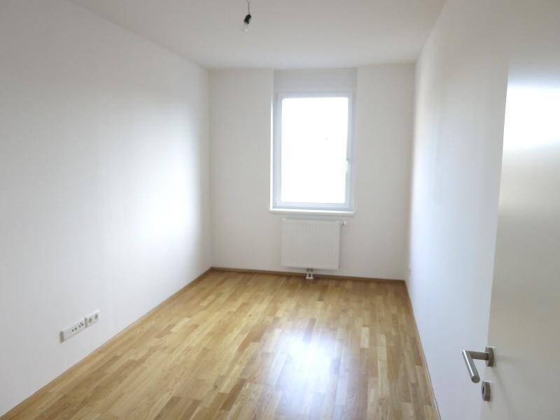 Helles Schlafzimmer mit Holzboden und einem Fenster, ideal für ein Kinderzimmer.