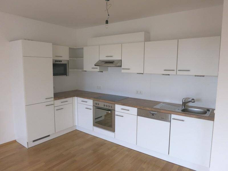 Moderne Einbauküche in Weiß mit Holz-Arbeitsplatte und integrierten Geräten.
