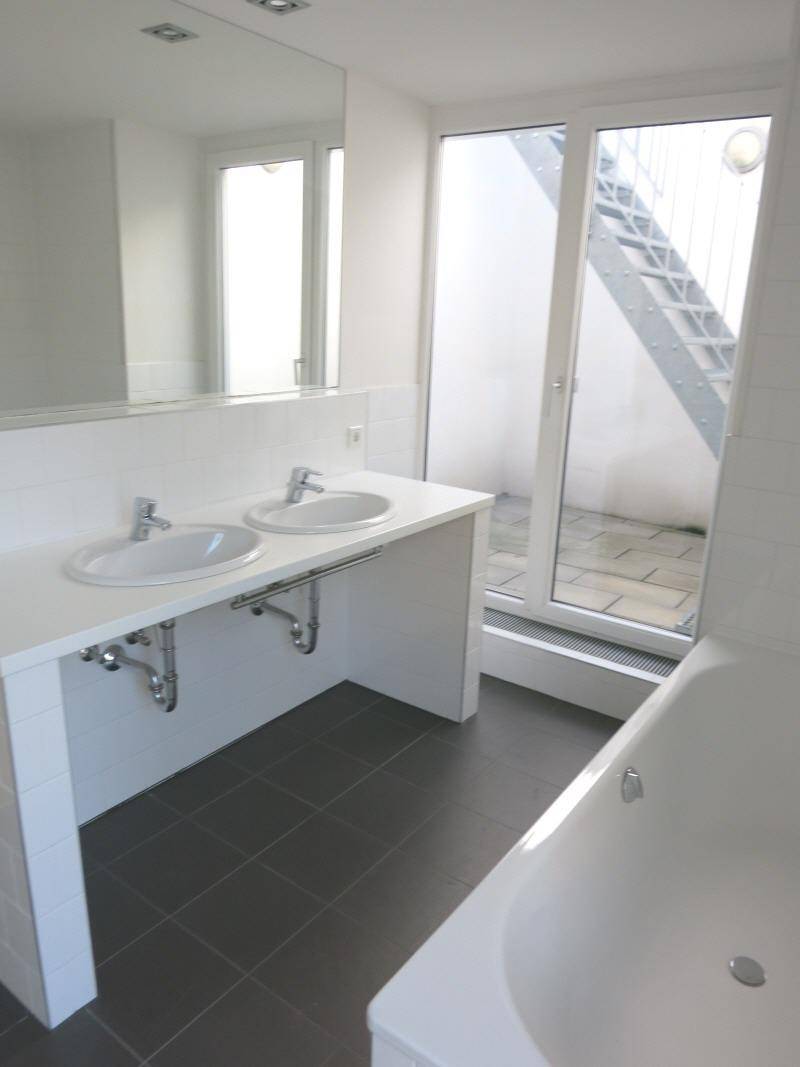 Modernes Badezimmer mit Doppelwaschbecken, Badewanne und Zugang nach draußen.