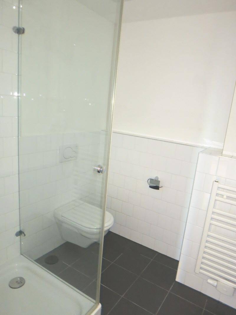 Modernes Badezimmer mit Duschkabine, Toilette und beheiztem Handtuchhalter.
