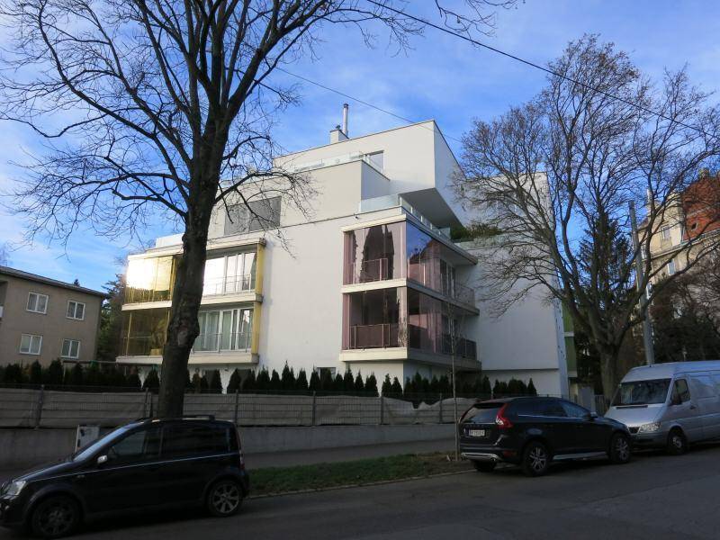 Moderne Wohnanlage mit weißer Fassade, großen Glasflächen und gepflegter Außenanlage.