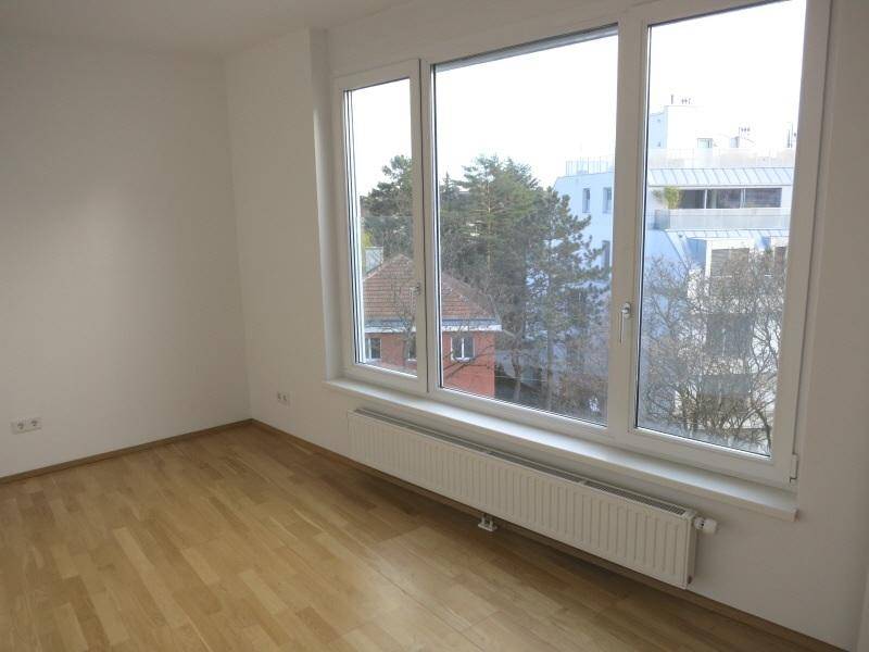 Geräumiges Zimmer mit Parkettboden und großen Fenstern, die viel Tageslicht hereinlassen.