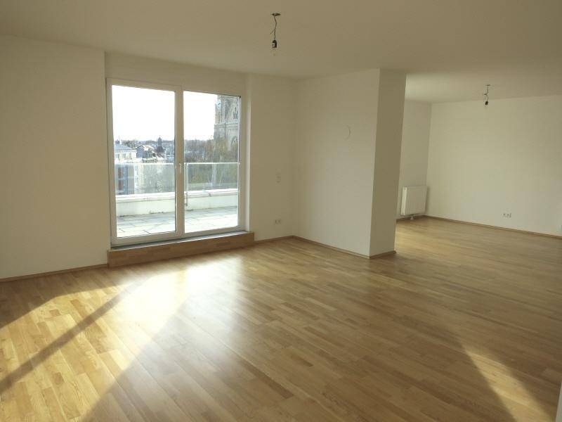 Lichtdurchflutetes Wohnzimmer mit Holzboden und Blick auf die Stadt und eine Kirche.