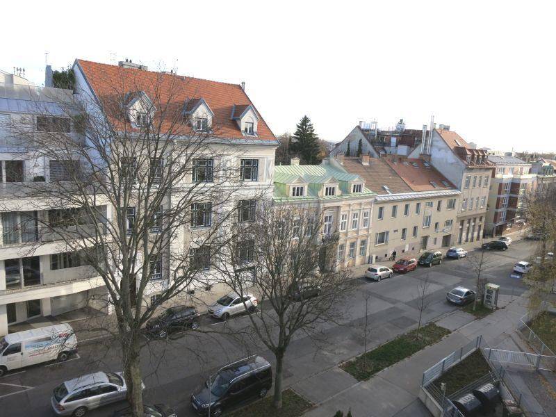 Weitblick über eine städtische Straße mit verschiedenen Gebäuden und herbstlichen Bäumen.