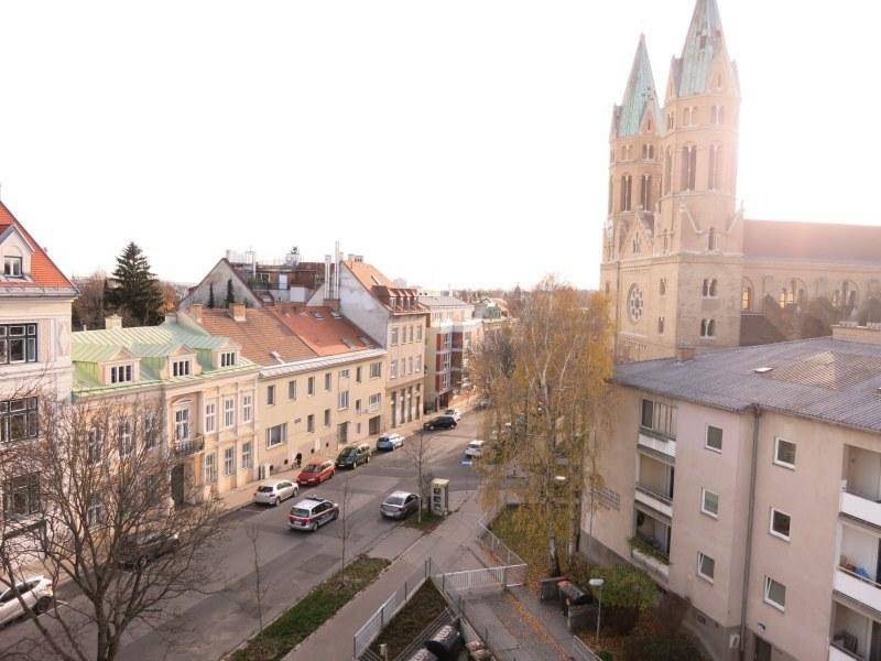 Panoramablick auf eine belebte Straße mit historischen Gebäuden und einer imposanten Kirche.