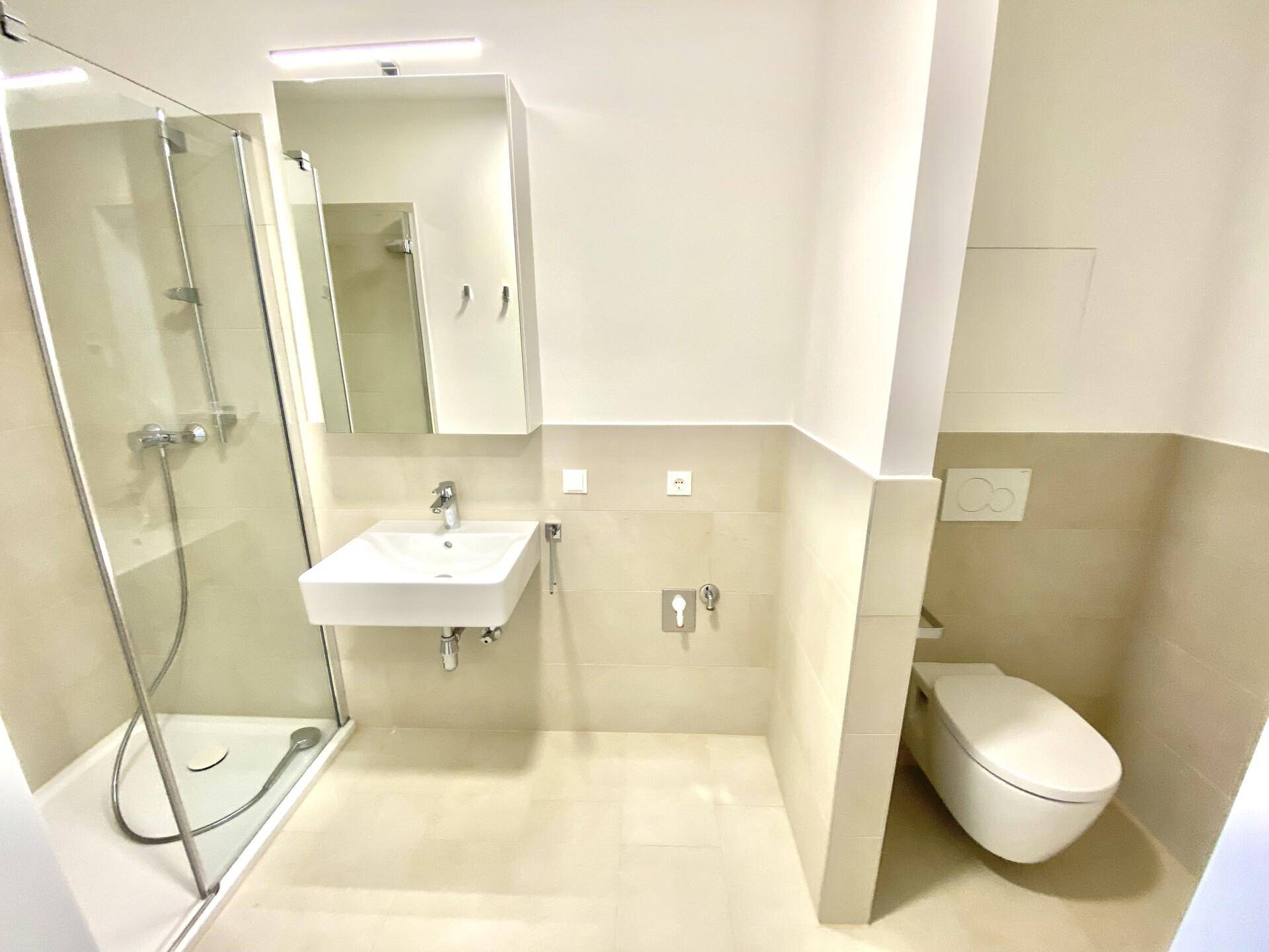 Modernes Badezimmer mit begehbarer Dusche, wandhängendem WC und hellem Fliesenboden.