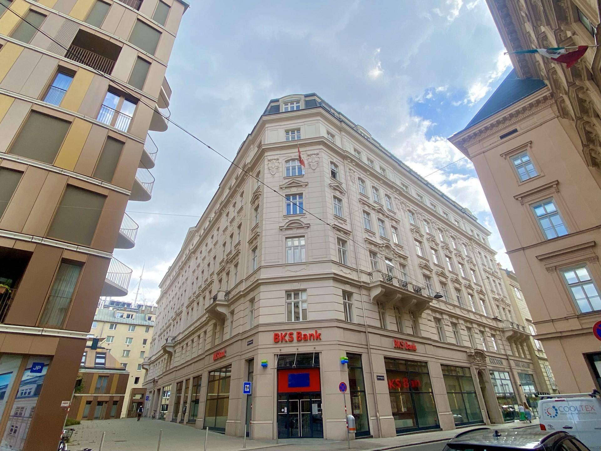Historisches Eckgebäude mit klassischer Fassade und Geschäften im Erdgeschoss in einer belebten Stadtansicht.