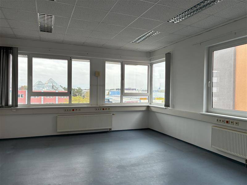 Weitläufiger Bürobereich mit vielen Fenstern, die eine weite Aussicht auf die städtische Umgebung ermöglichen und viel Licht spenden.