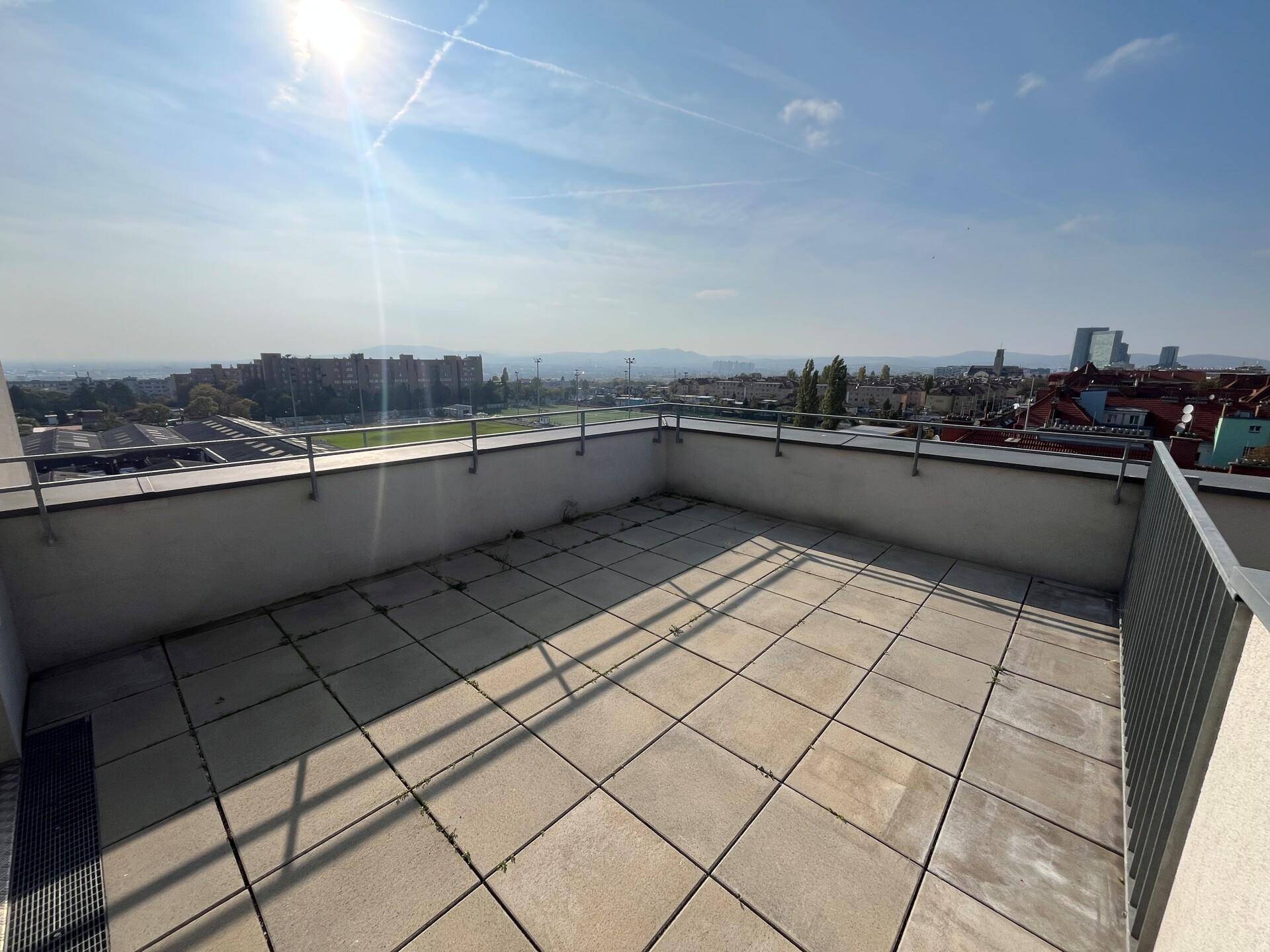 Sonnige Dachterrasse mit urbanem Panorama und klarem Himmel, ideal für Entspannung im Freien.