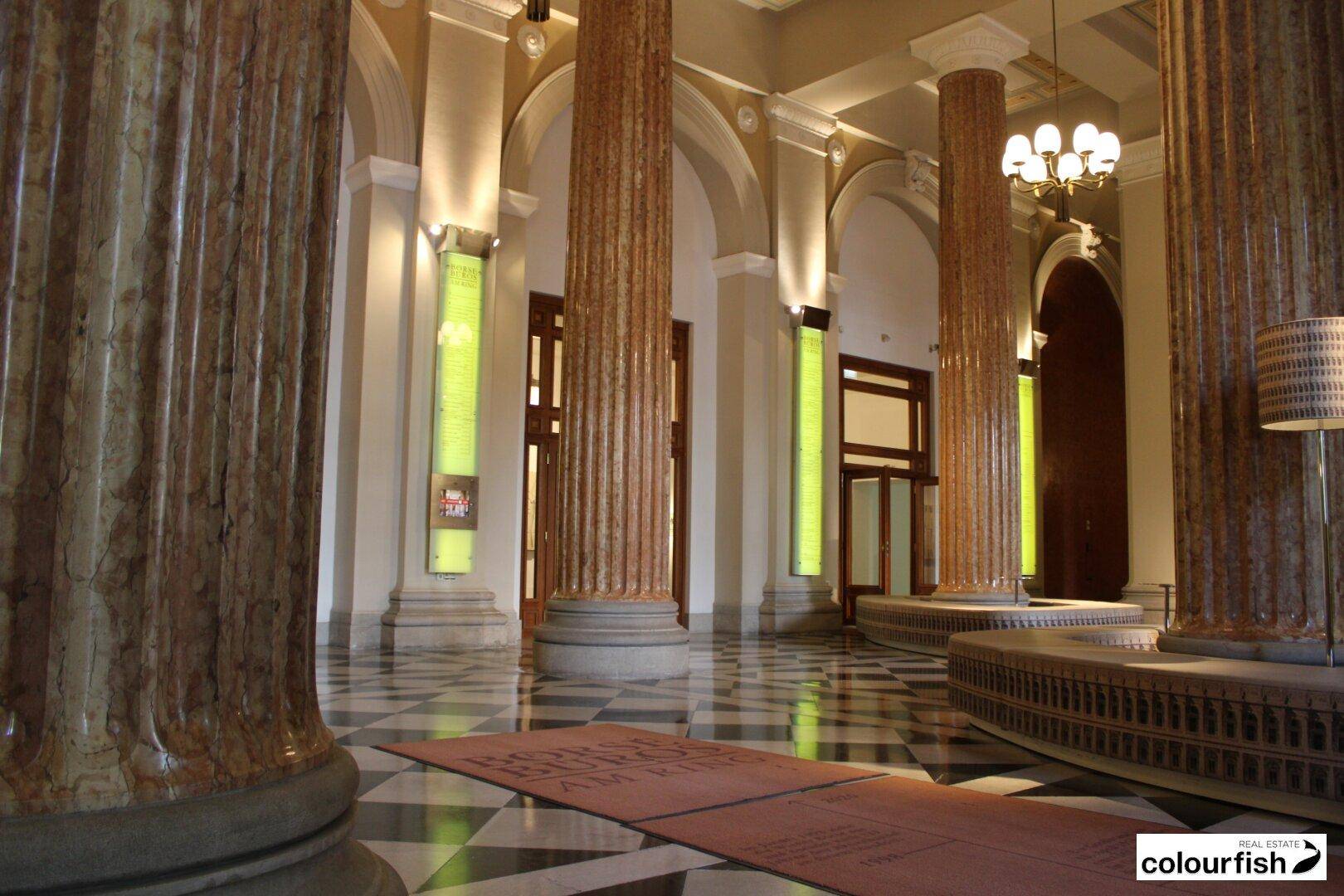 Prächtige Lobby mit hohen Marmorsäulen, kariertem Boden und indirekter Beleuchtung, die eine luxuriöse Atmosphäre schafft.