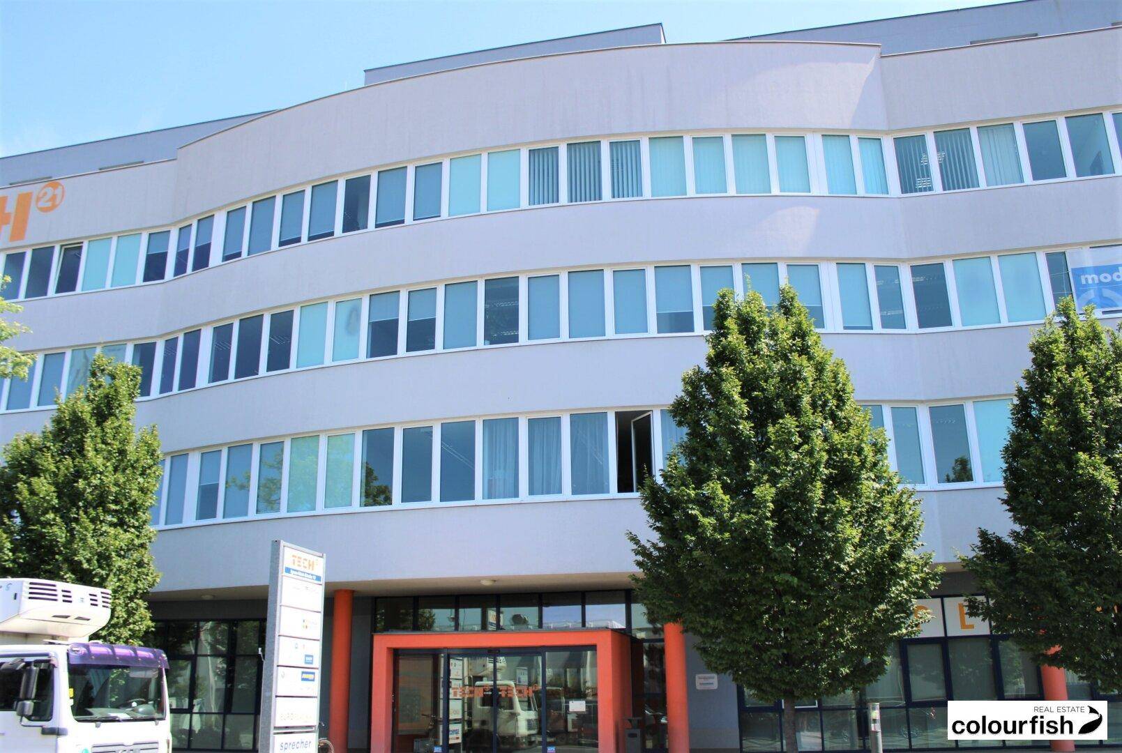 Nahaufnahme der modernen Bürogebäude-Fassade mit großen Fenstern und Eingangsbereich.