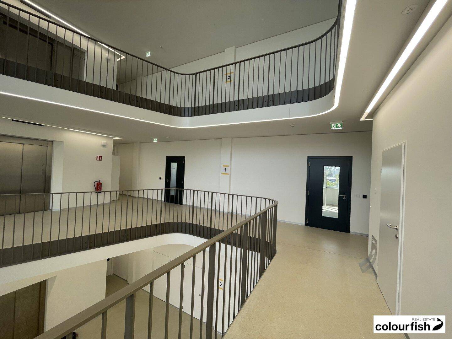 Heller, moderner Flur im Obergeschoss mit eleganten Geländern, integrierter Beleuchtung und Zugang zu weiteren Räumen.