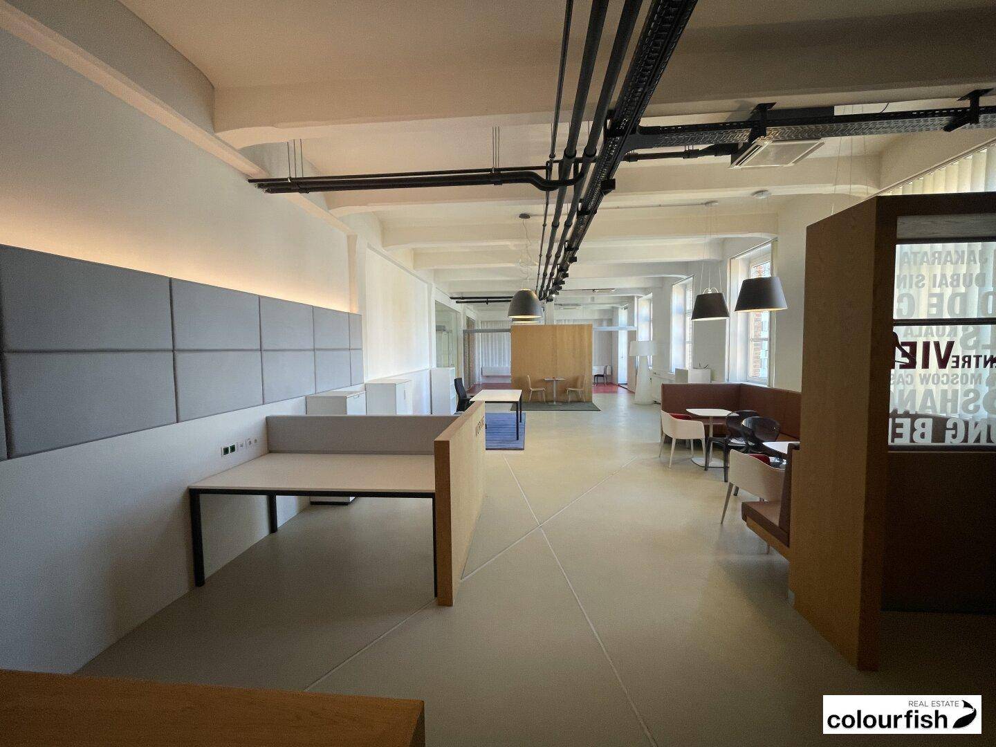 Großraumbüro mit flexiblen Arbeitsbereichen, schallabsorbierenden Paneelen und industriellem Decken-Design.