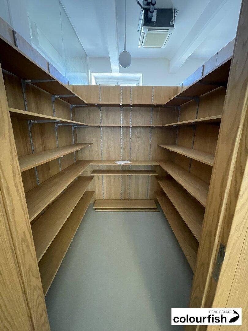 Praktischer Abstellraum mit vielen Holzregalen für Lagerung und Organisation, gut beleuchtet.
