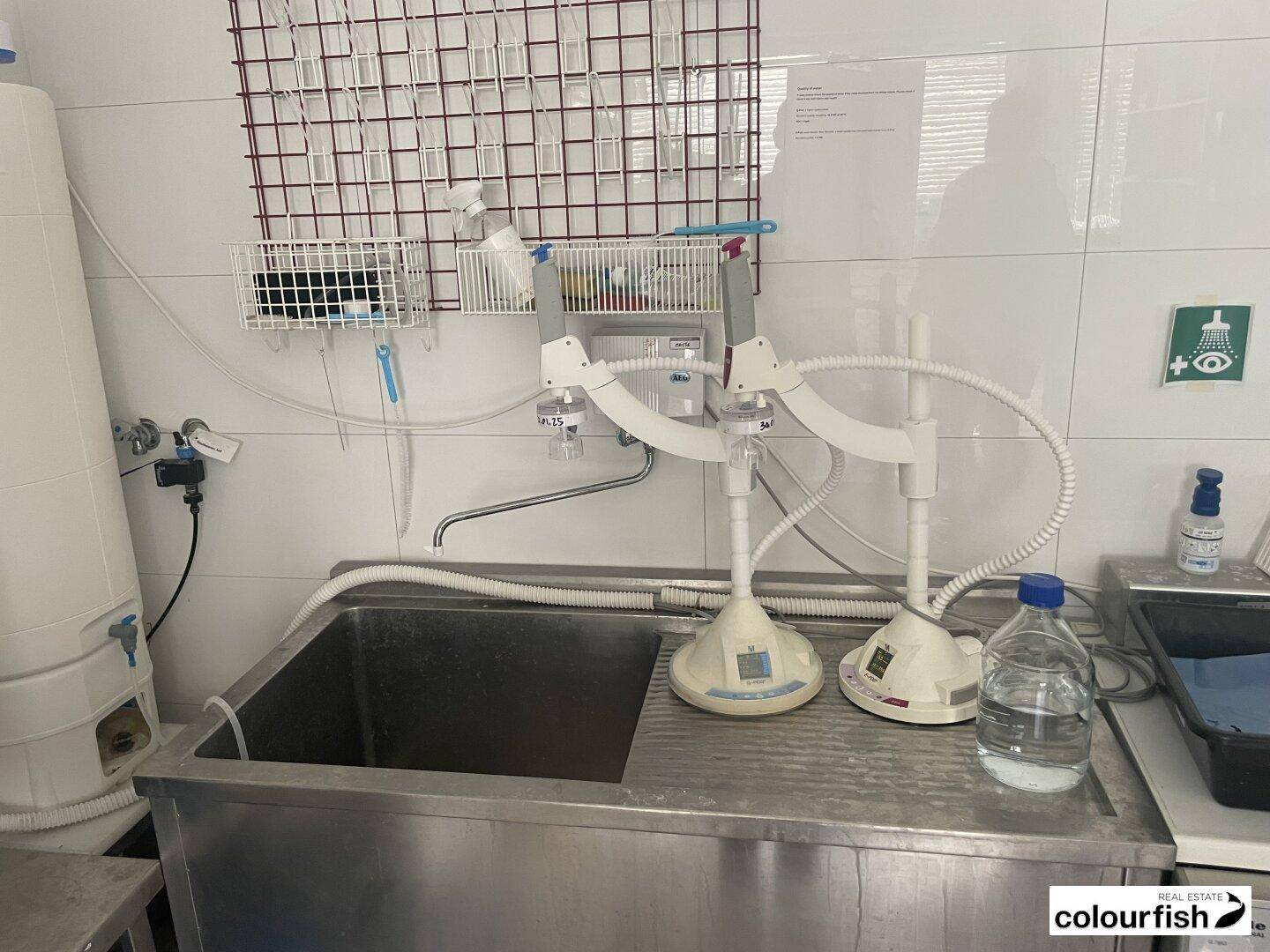 Industrielles Waschbecken aus Edelstahl mit speziellen Armaturen und Notdusche in einem funktionalen Laborbereich.