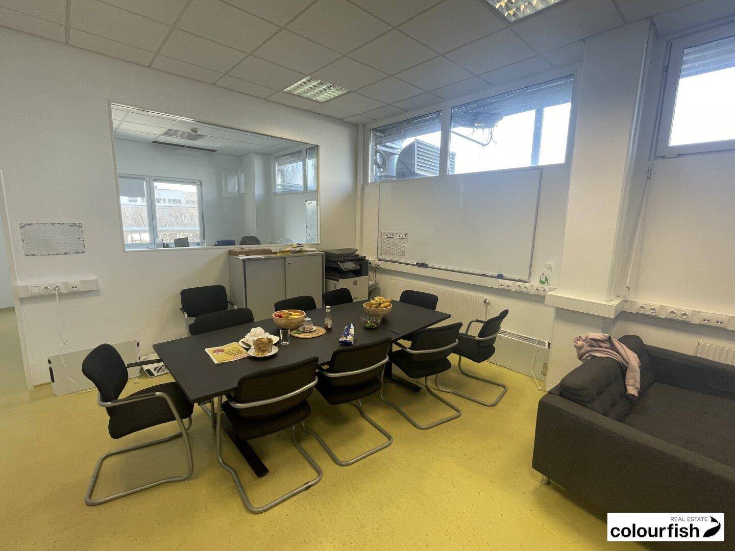Geräumiger Konferenzraum mit großem Tisch, Stühlen und einem Whiteboard, ideal für Besprechungen und Präsentationen.