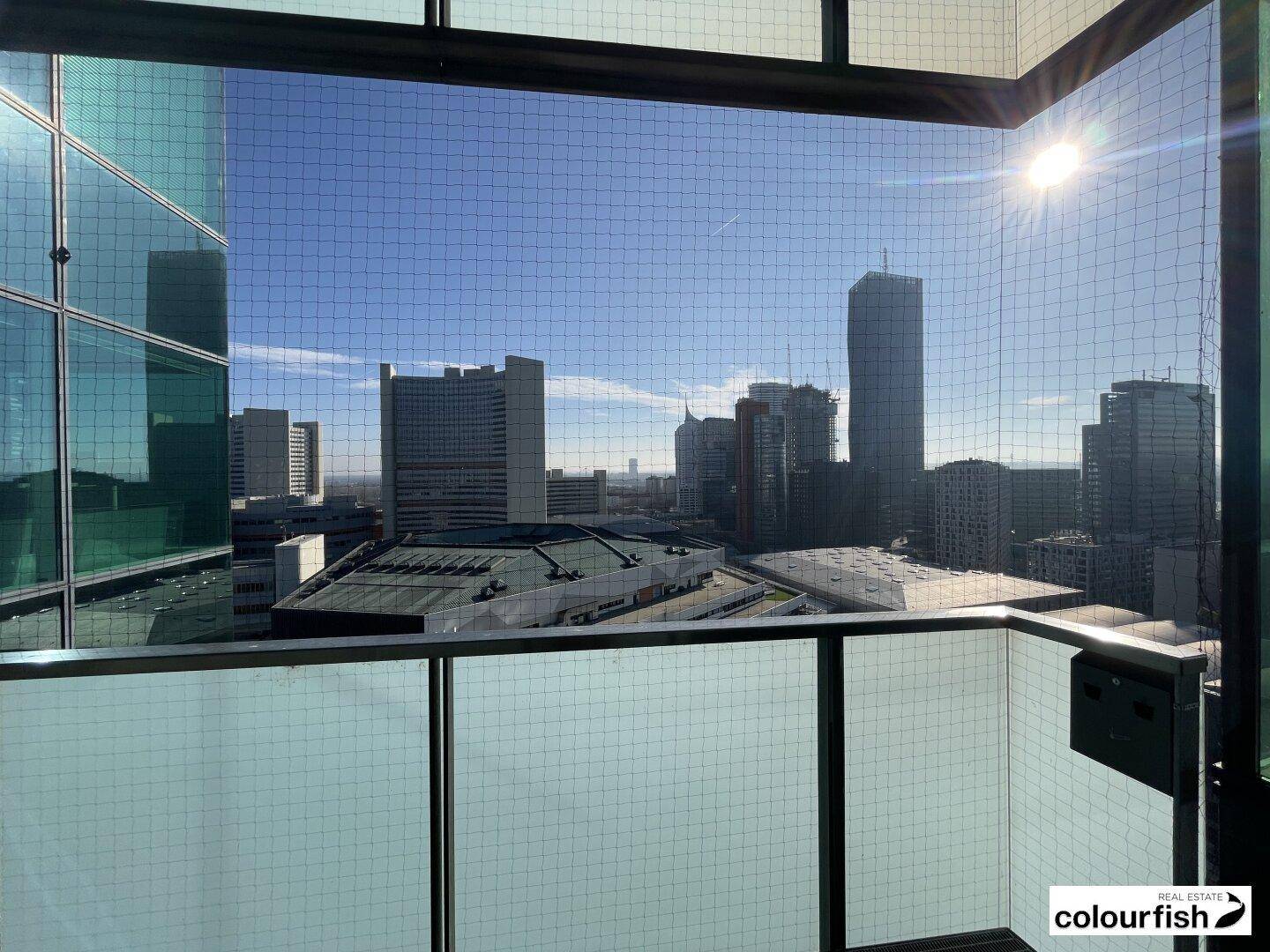 Balkon mit weitem Blick auf die städtische Skyline und umliegende Hochhäuser unter blauem Himmel.