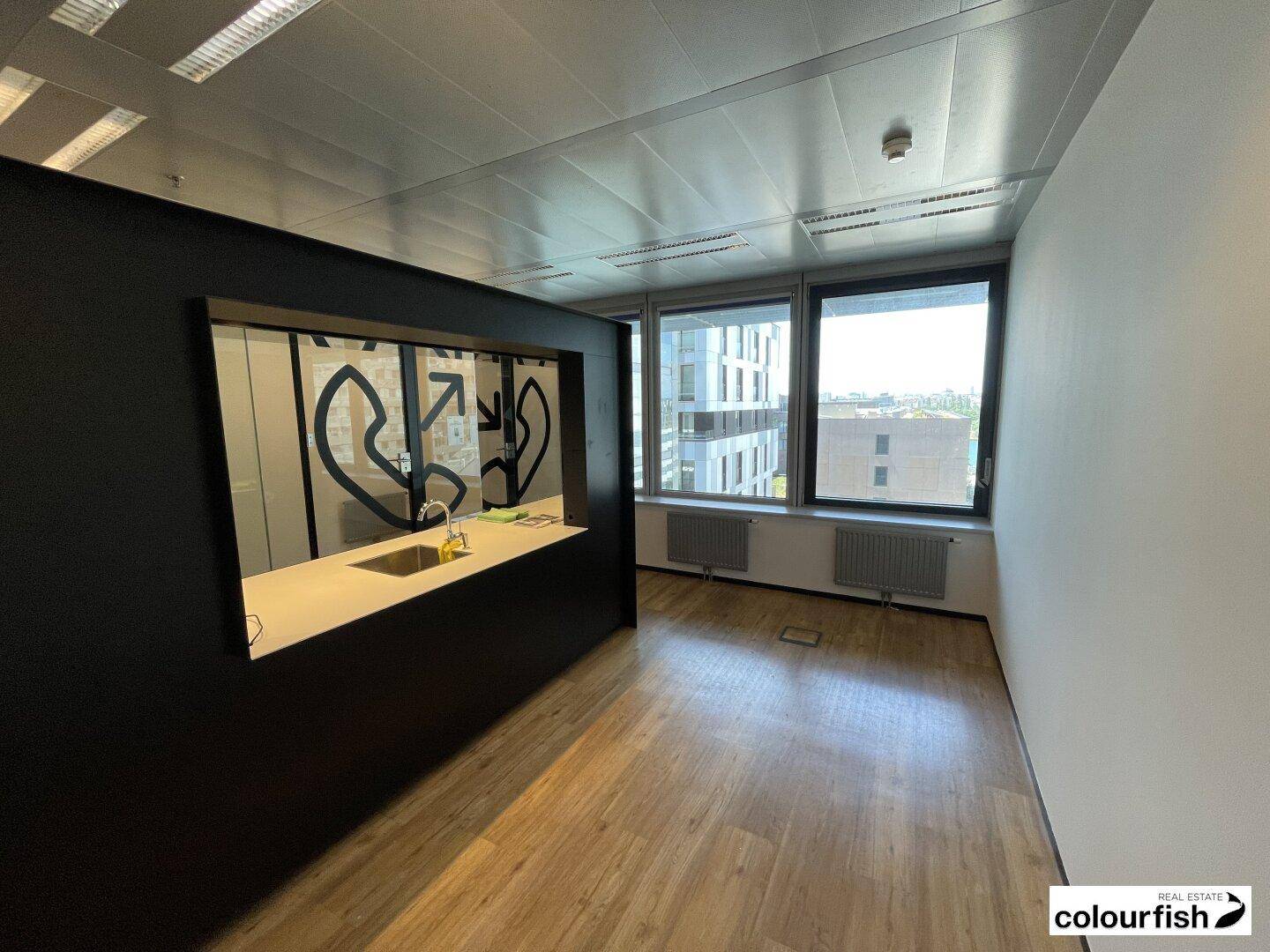 Helles Büro mit Holzboden und einer integrierten Küchenzeile, ideal für Pausen und kleine Mahlzeiten.