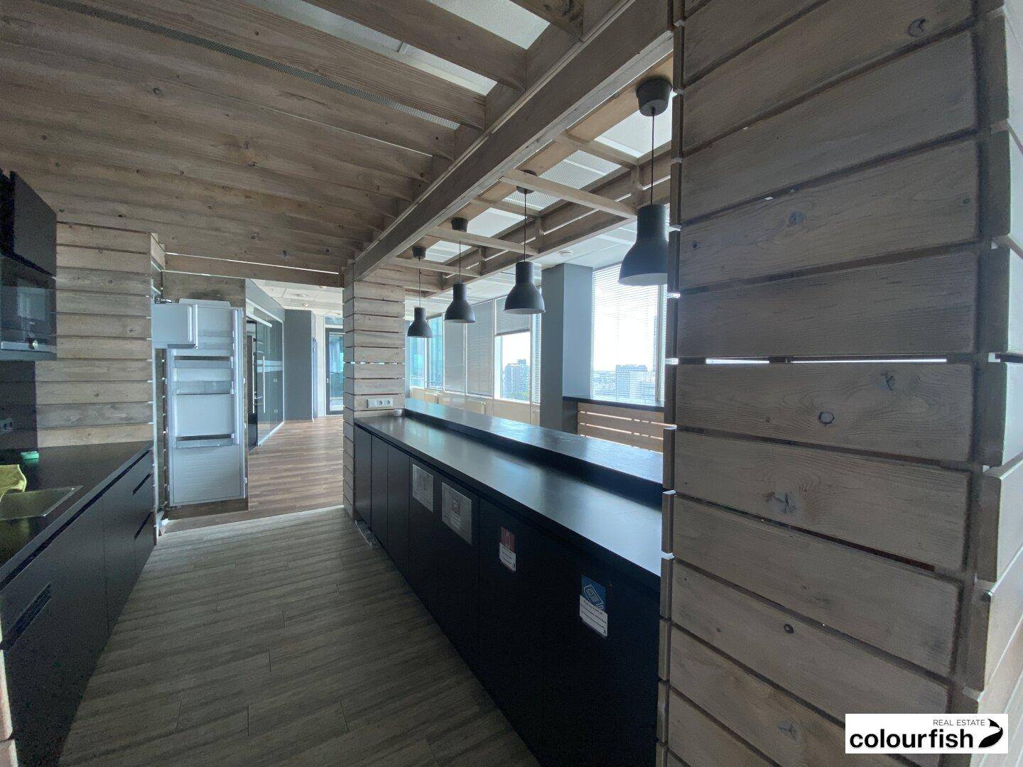 Moderne Küche mit Holzverkleidung an Wänden und Decke, dunklen Arbeitsplatten und Hängelampen.