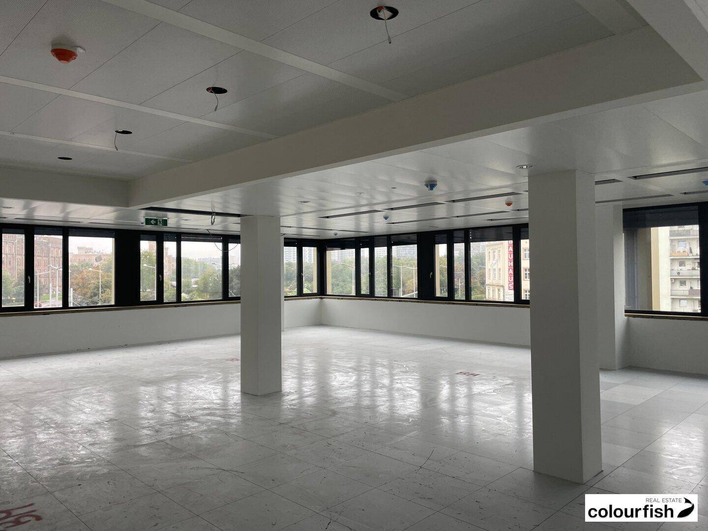 Geräumiges, leeres Büro mit großen Fenstern und Fliesenboden, bereit für individuelle Gestaltung.
