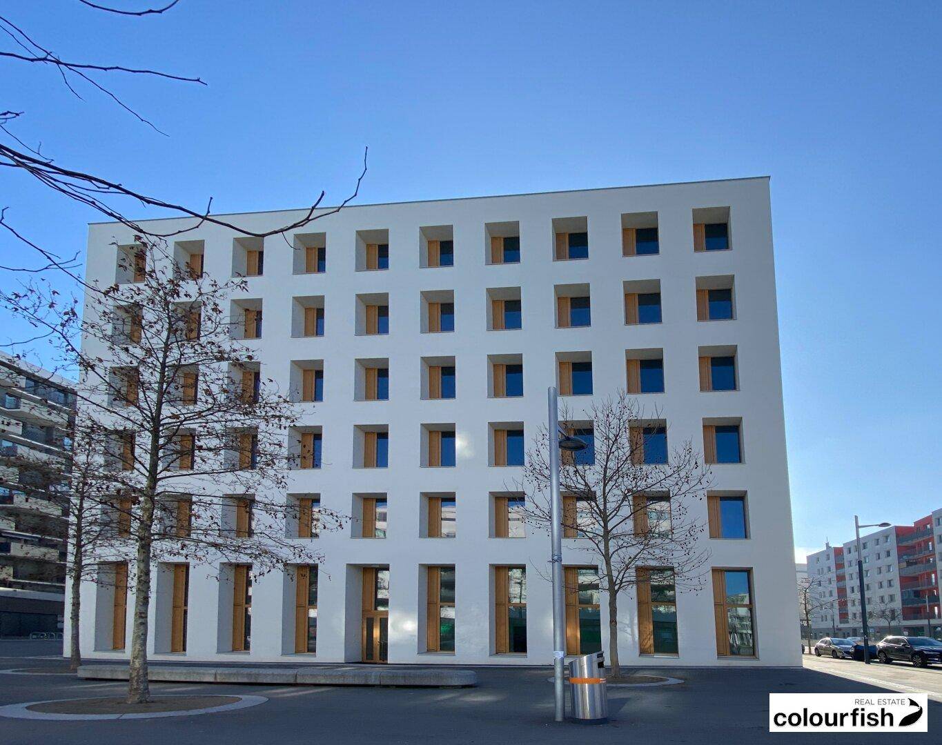 Geradlinige Fassade eines modernen Gebäudes mit vielen quadratischen Fenstern und klarem Himmel.