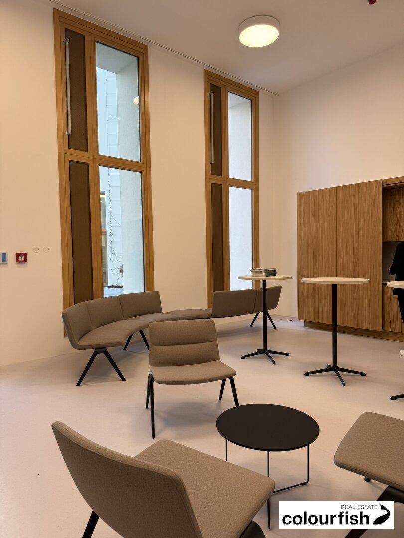 Moderner Loungebereich mit bequemen Sitzgelegenheiten und hohen Fenstern, ideal für Pausen.