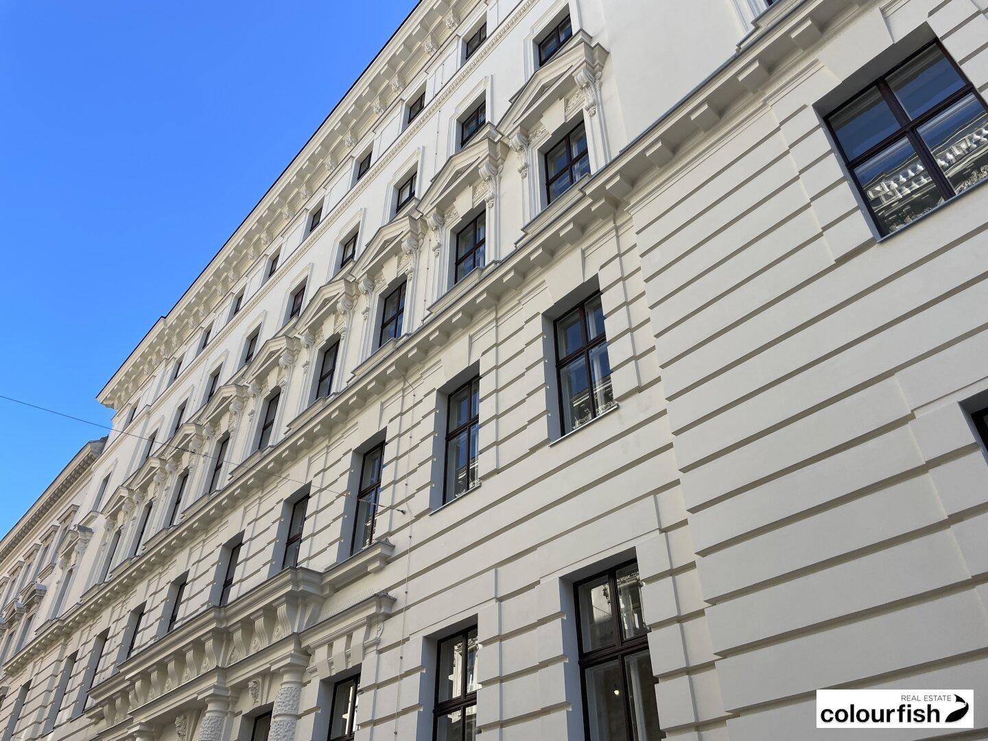 Eindrucksvolle weiße Fassade eines historischen Gebäudes mit vielen Fenstern und klassischer Architektur.