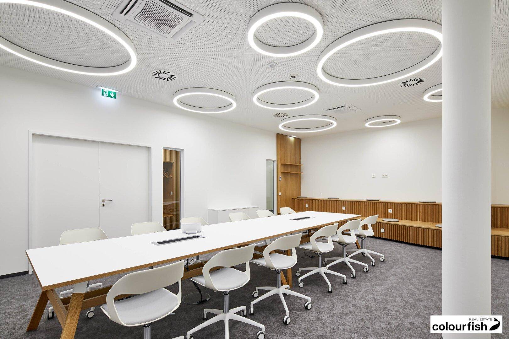 Moderner Konferenzraum mit einzigartigen runden Deckenleuchten, langem Tisch und eleganter Holzvertäfelung.