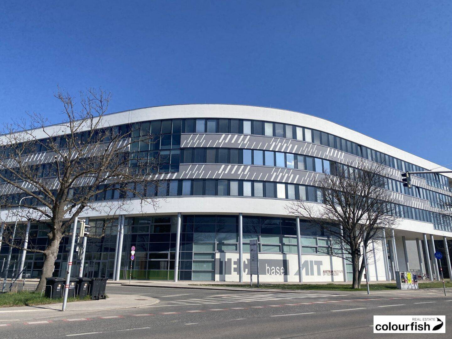 Moderne Bürogebäude-Fassade mit geschwungenen Linien, großen Glasflächen und vielen Fenstern.