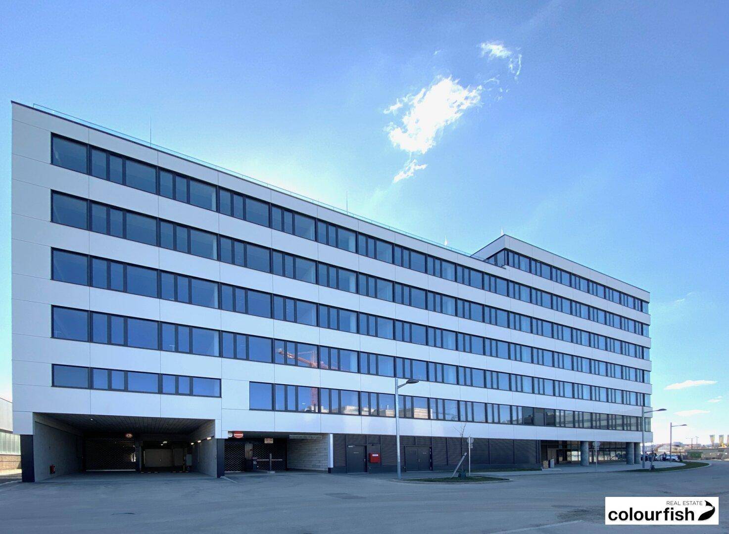 Modernes Bürogebäude mit klarer Architektur und zahlreichen Fenstern unter blauem Himmel.