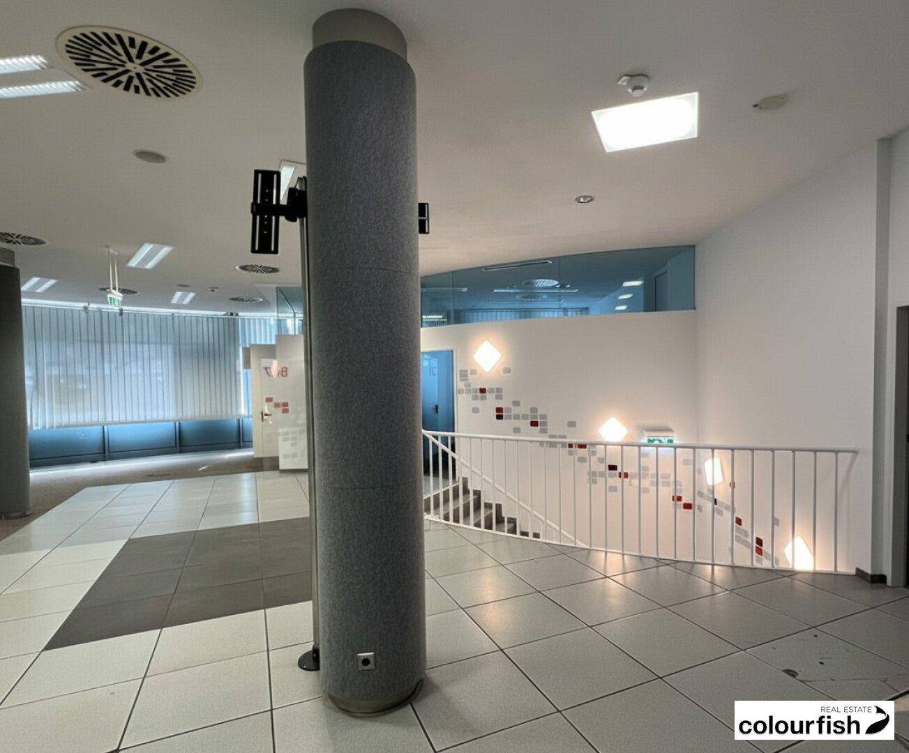 Heller Flurbereich mit Treppenaufgang, Fliesenboden und modernen Wandleuchten.