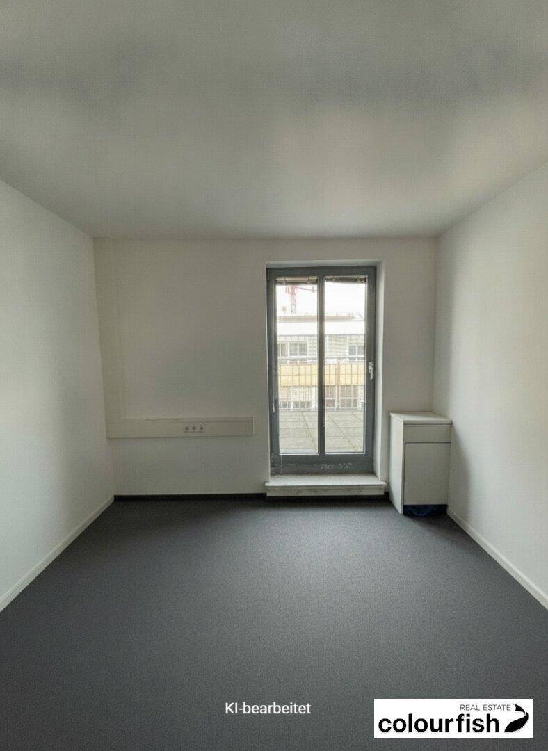 Heller Raum mit grauen Bodenbelag und einem Fenster, ideal als Büro oder Arbeitszimmer.