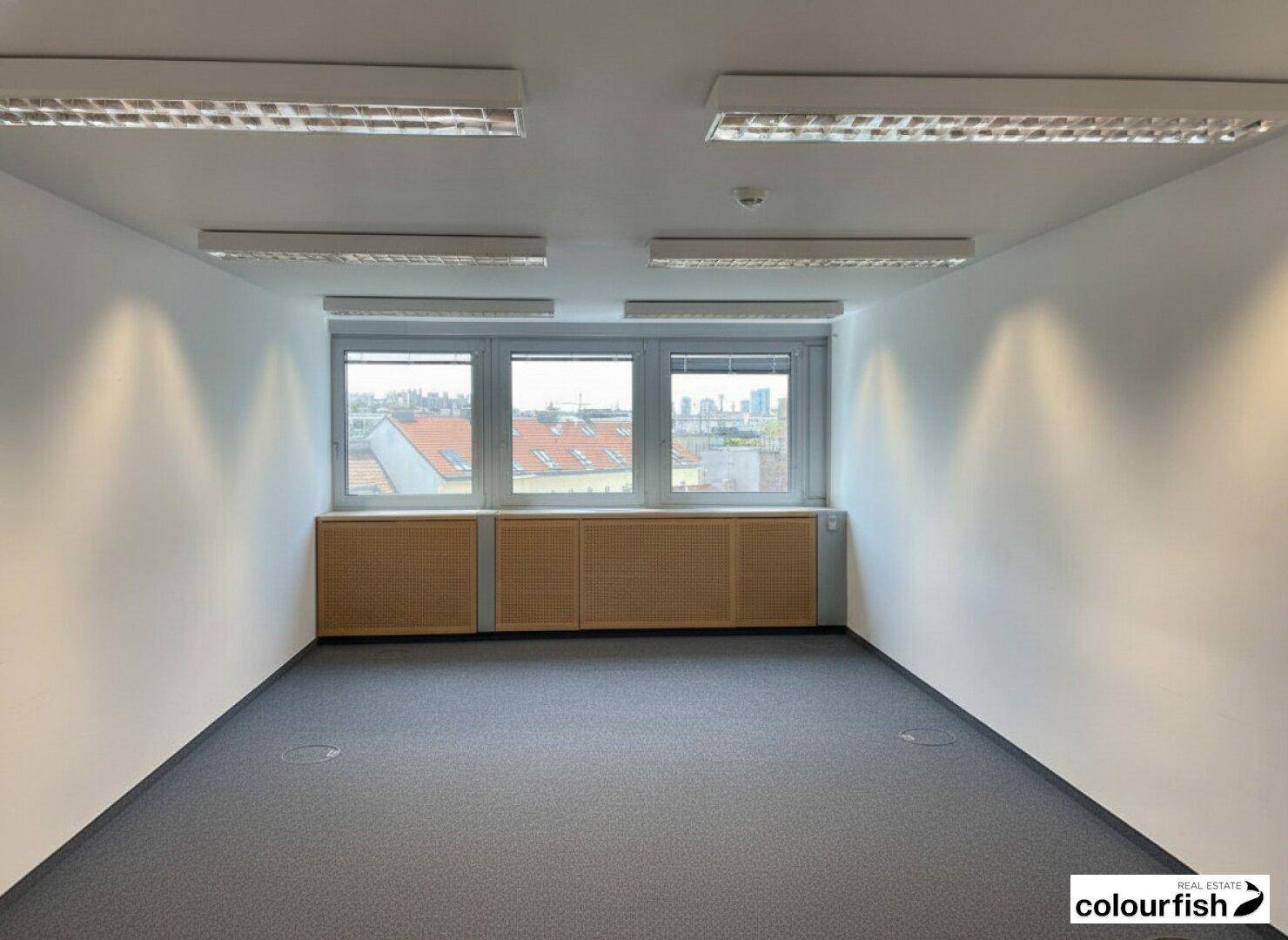 Helles Büro mit drei Fenstern, Einbauschränken und Teppichboden, bietet eine weite Aussicht über die Stadt.